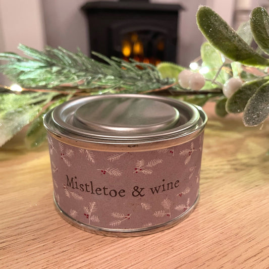 Mistletoe and wine scented christmas candle styled on a coffee table with a mistletoe garland in a living room.