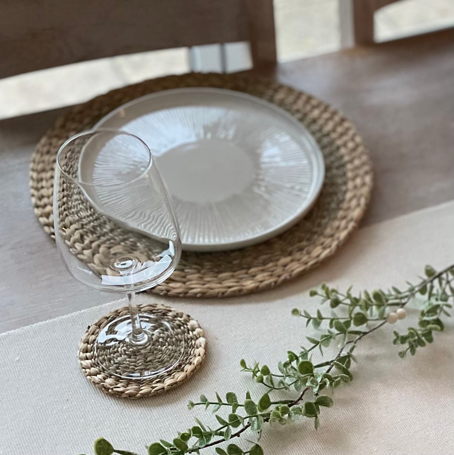 Eco friendly seagrass and water hyacinth coasters paired with matching placemats. Styled on a white linen tablecloth.