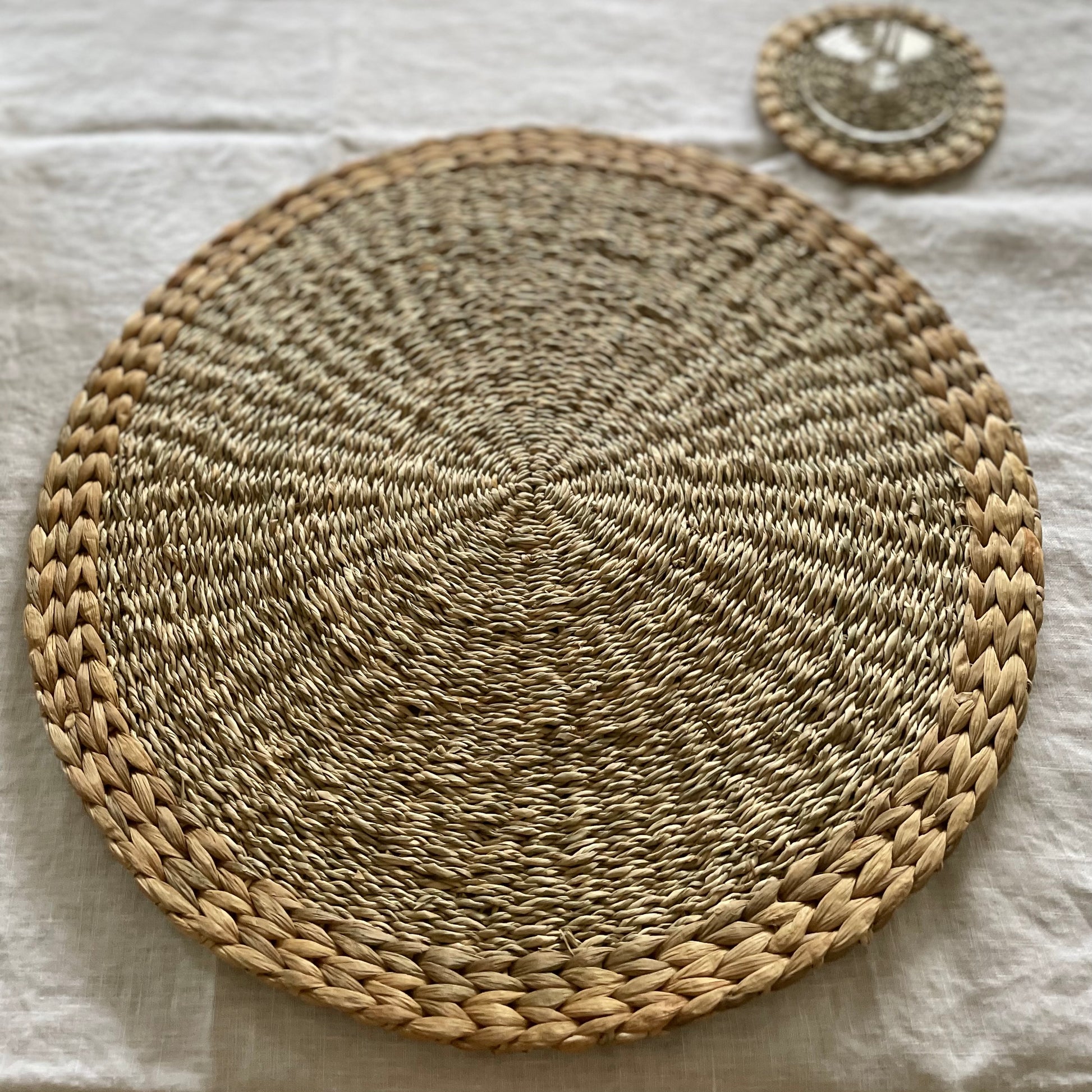 Handmade seagrass and water hyacinth placemats. Styled on a white linen tablecloth.