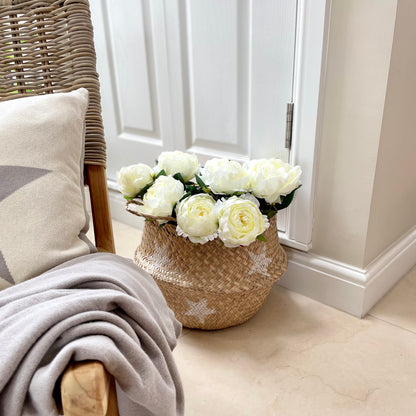 Handmade star detailed seagrass basket with natural woven texture and handles, styled in a cosy, rustic living space.