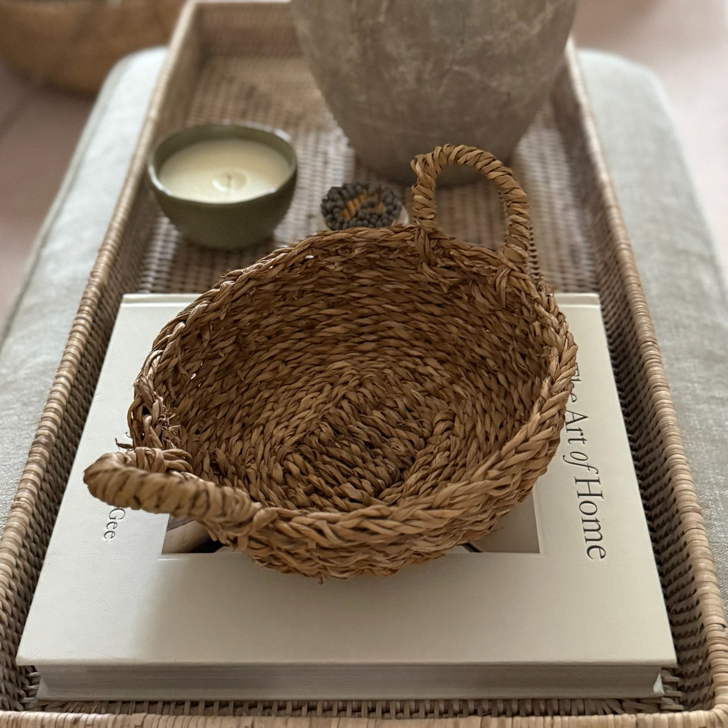 Woven basket on a book with a candle and vase in the background