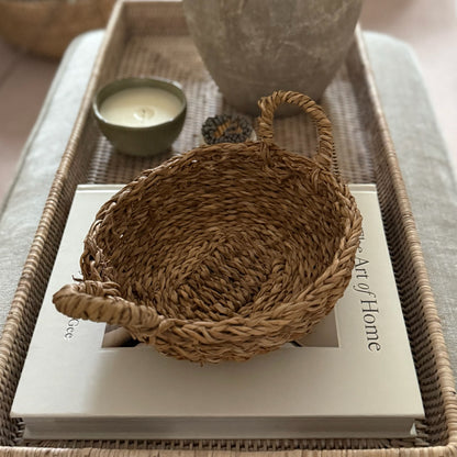 Woven basket on a book with a candle and vase in the background