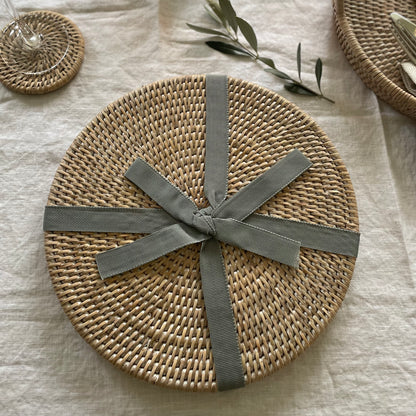 Set of 2 round whitewashed rattan placemats. Styled on a white linen tablecloth.
