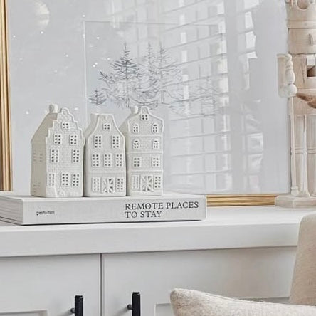 Decorative scene with 3 white houses that look like canal dutch style houses and a sign on a shelf.