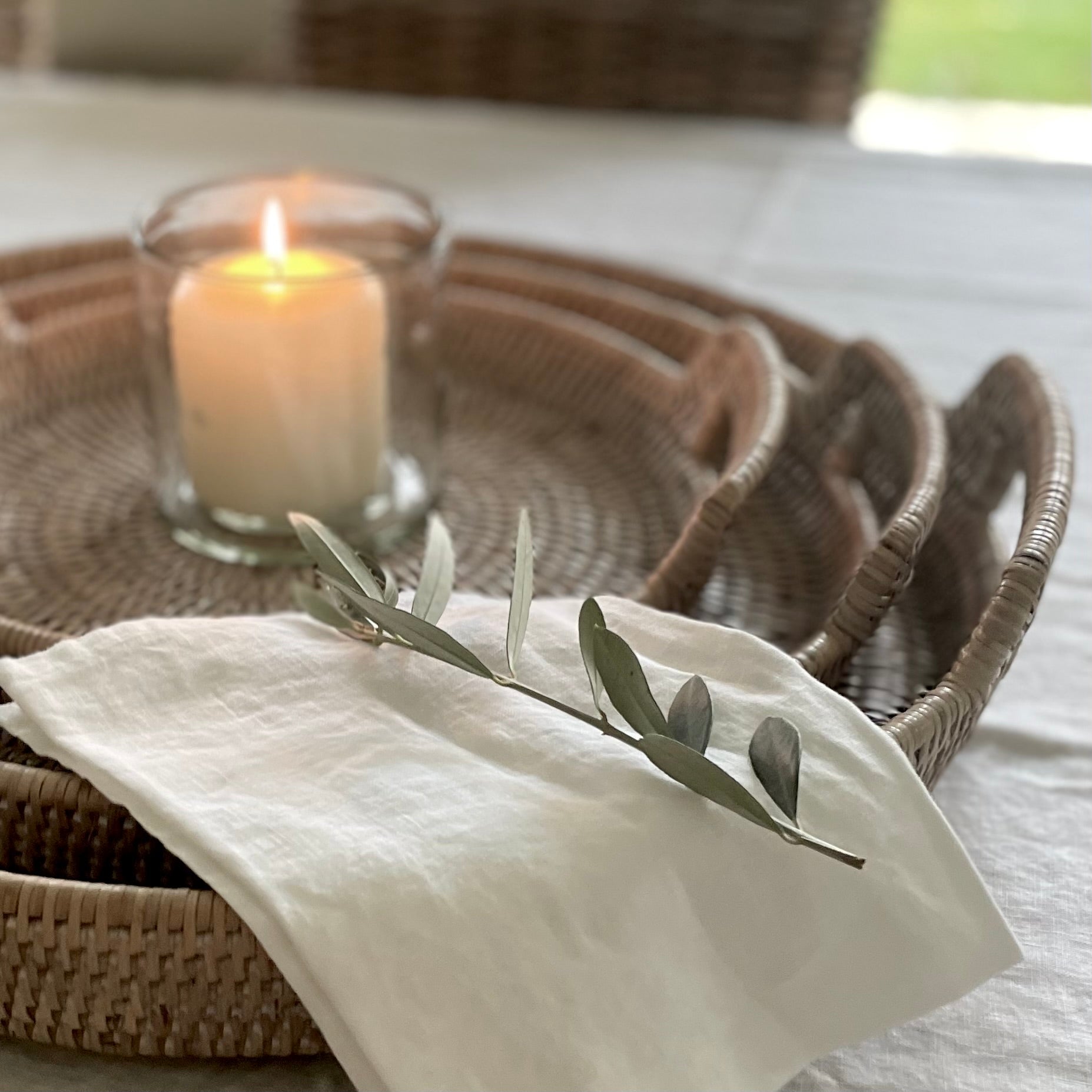 Softening white 100% linen napkin close up texture. Styled on rattan round trays on a dining table.