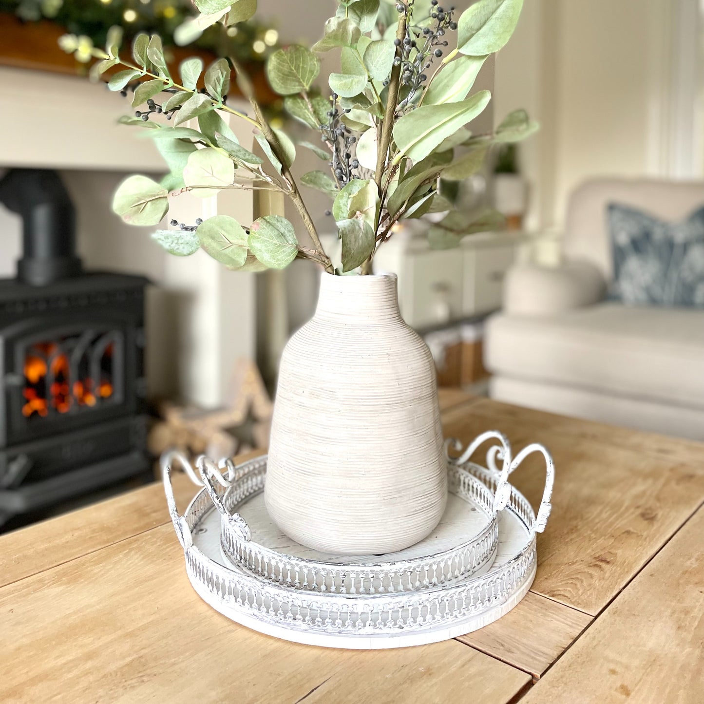 Round ornate white washed trays with handles, styled on a coffee table in a cosy living room.