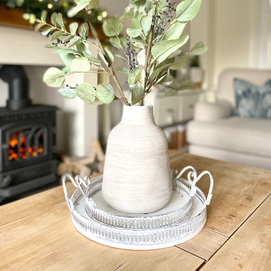 Round ornate white washed trays with handles, styled on a coffee table in a cosy living room.