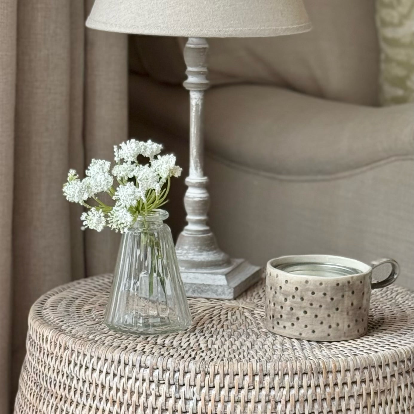 Tapered pyramid style glass bud vase holding a single stem, styled on a windowsill in a calm, neutral interior.
