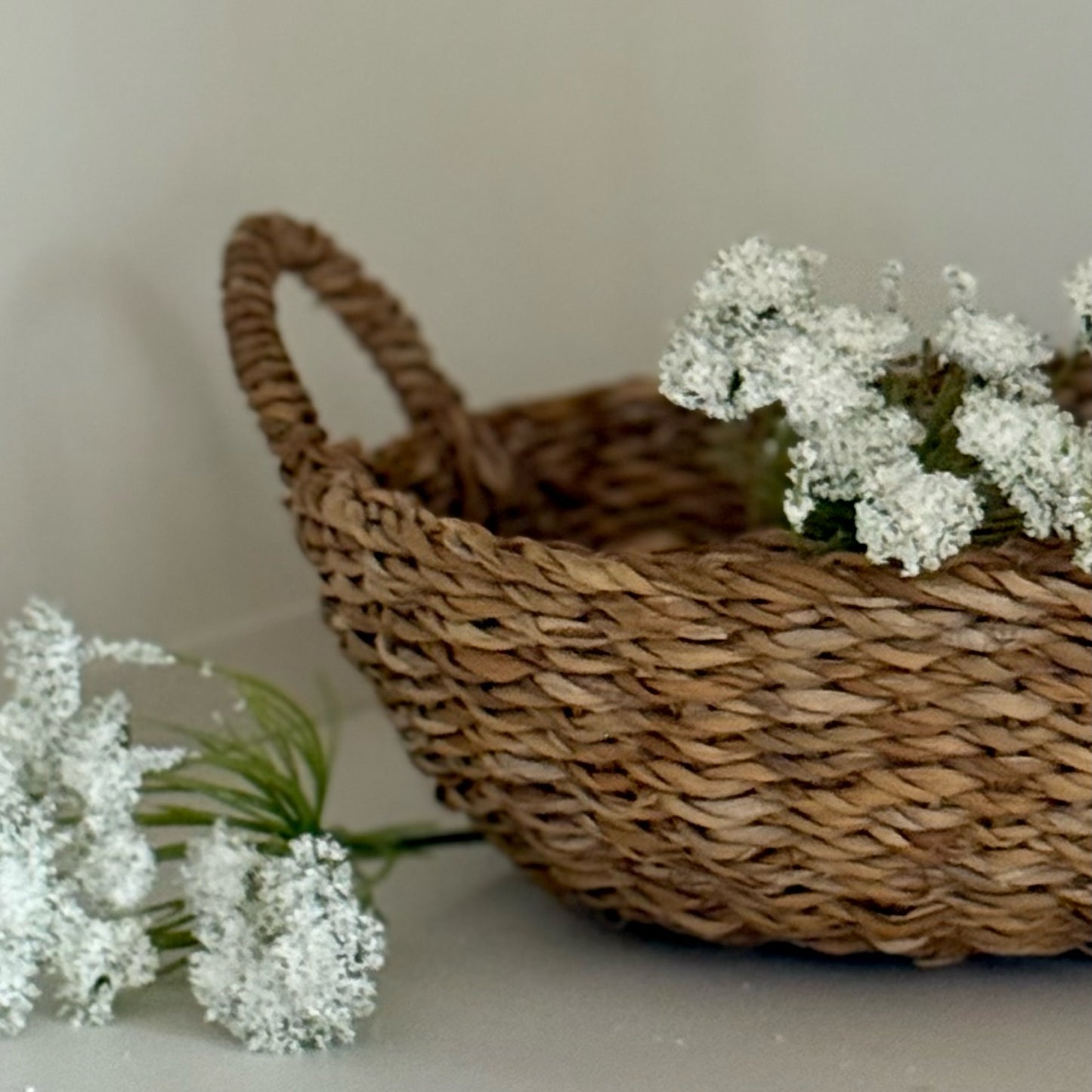Woven basket with white flowers on a neutral background