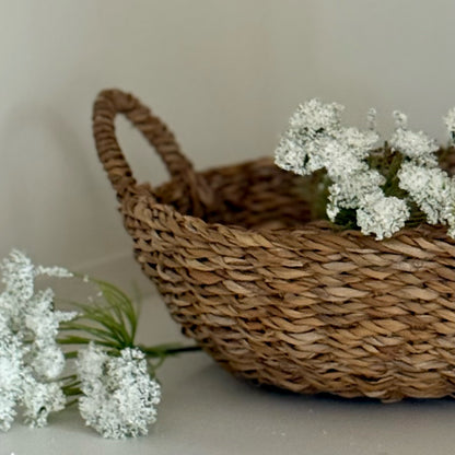 Woven basket with white flowers on a neutral background