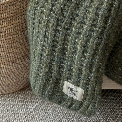 Decorative deep green throw with rich melange texture, perfect for cosy layering in neutral or seasonal interiors.