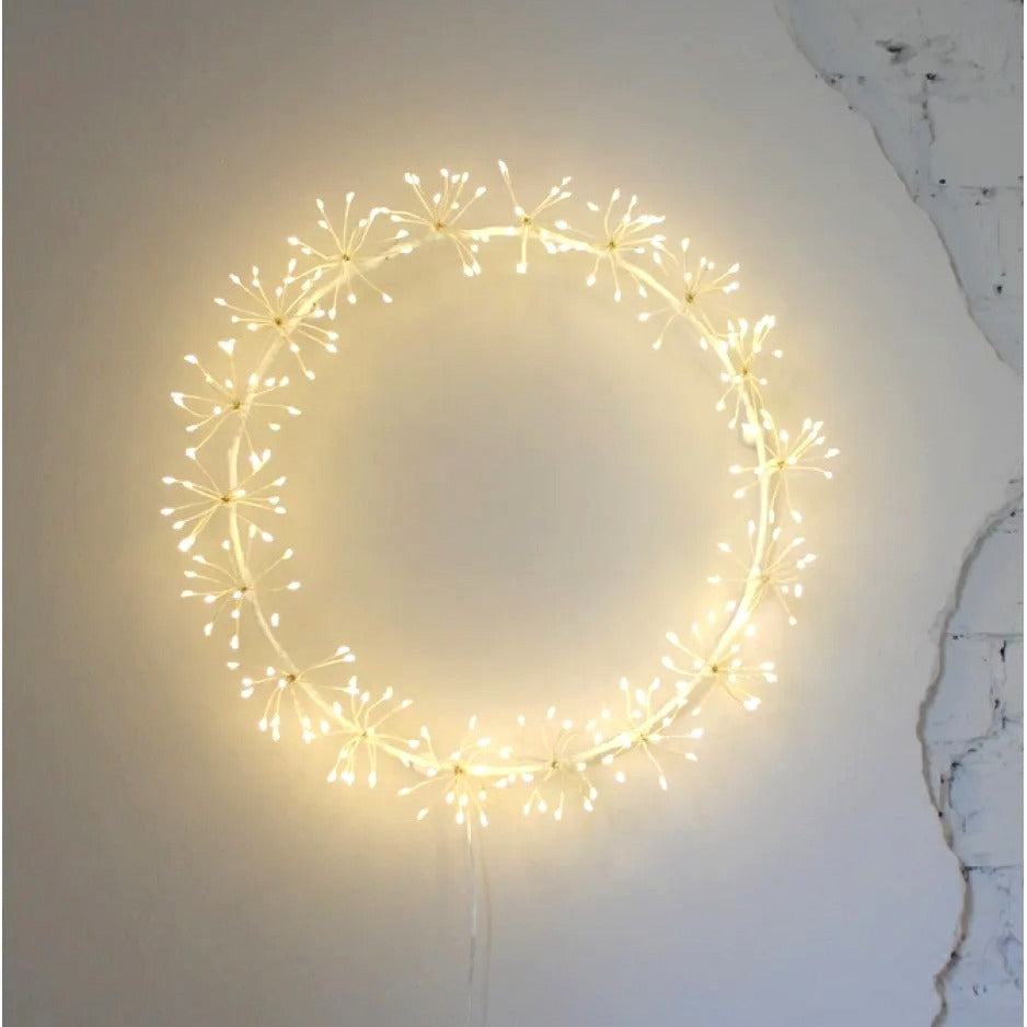 LED starburst wreath glowing with warm white lights on a rustic wall, creating a soft festive ambiance