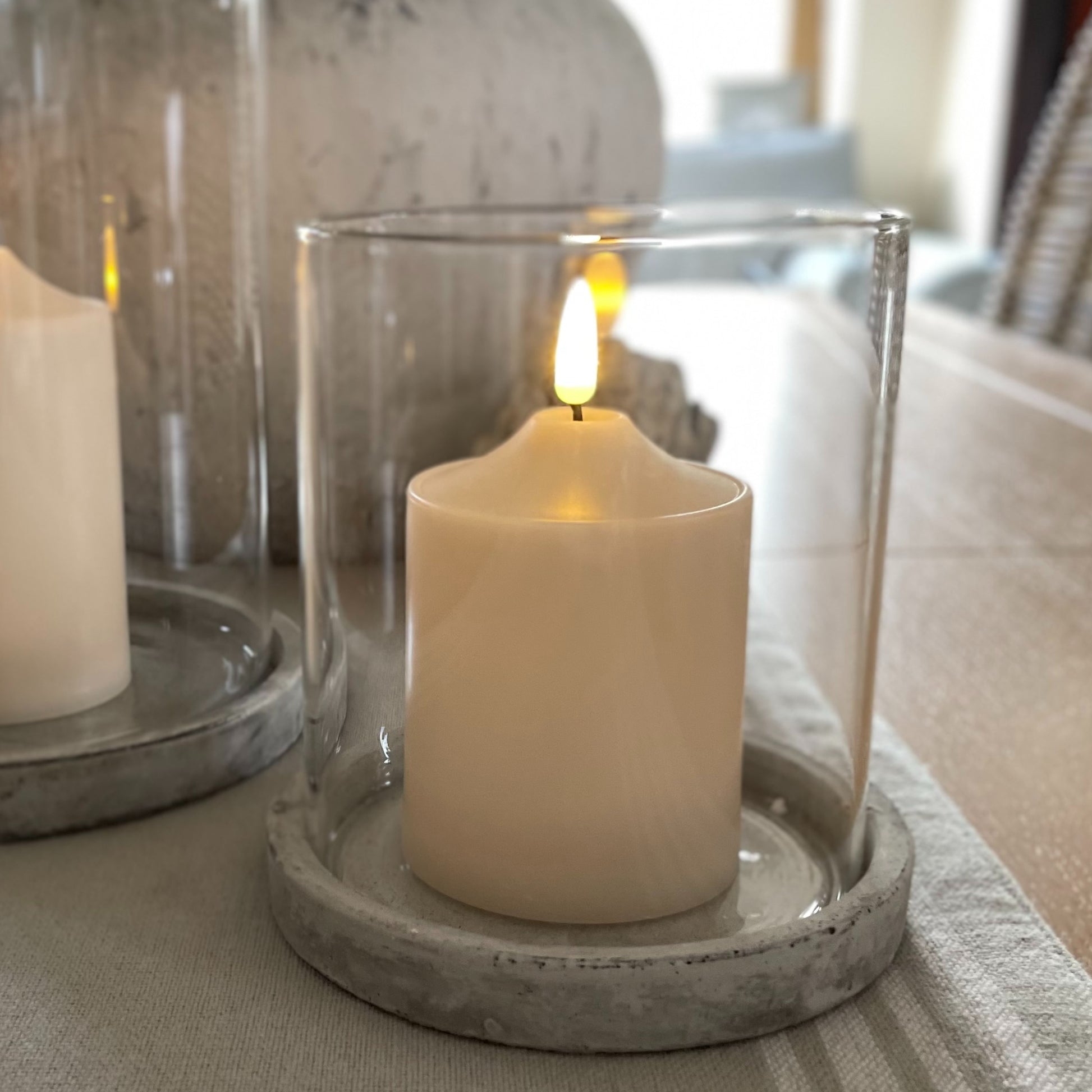 Athena hurricane with natural earthy grey stone base and glass shade styled on a wooden dining table.