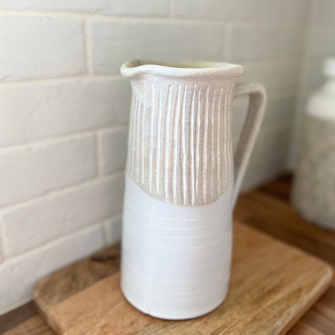 Rustic stoneware jug with light grey textured top and off white gloss glazed base, styled on a wooden work top.