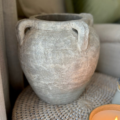 Gray terracotta pot with handles on a woven surface