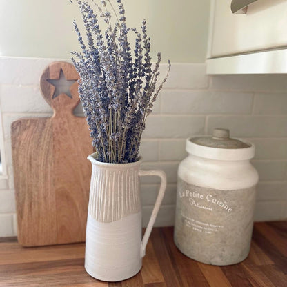Rustic stoneware jug with light grey textured top and off-white gloss glazed base, styled on a wooden shelf with dried lavender.
