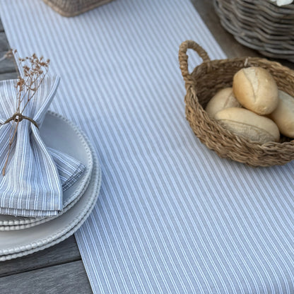 Table setting with striped table runner, bread basket, and plates.