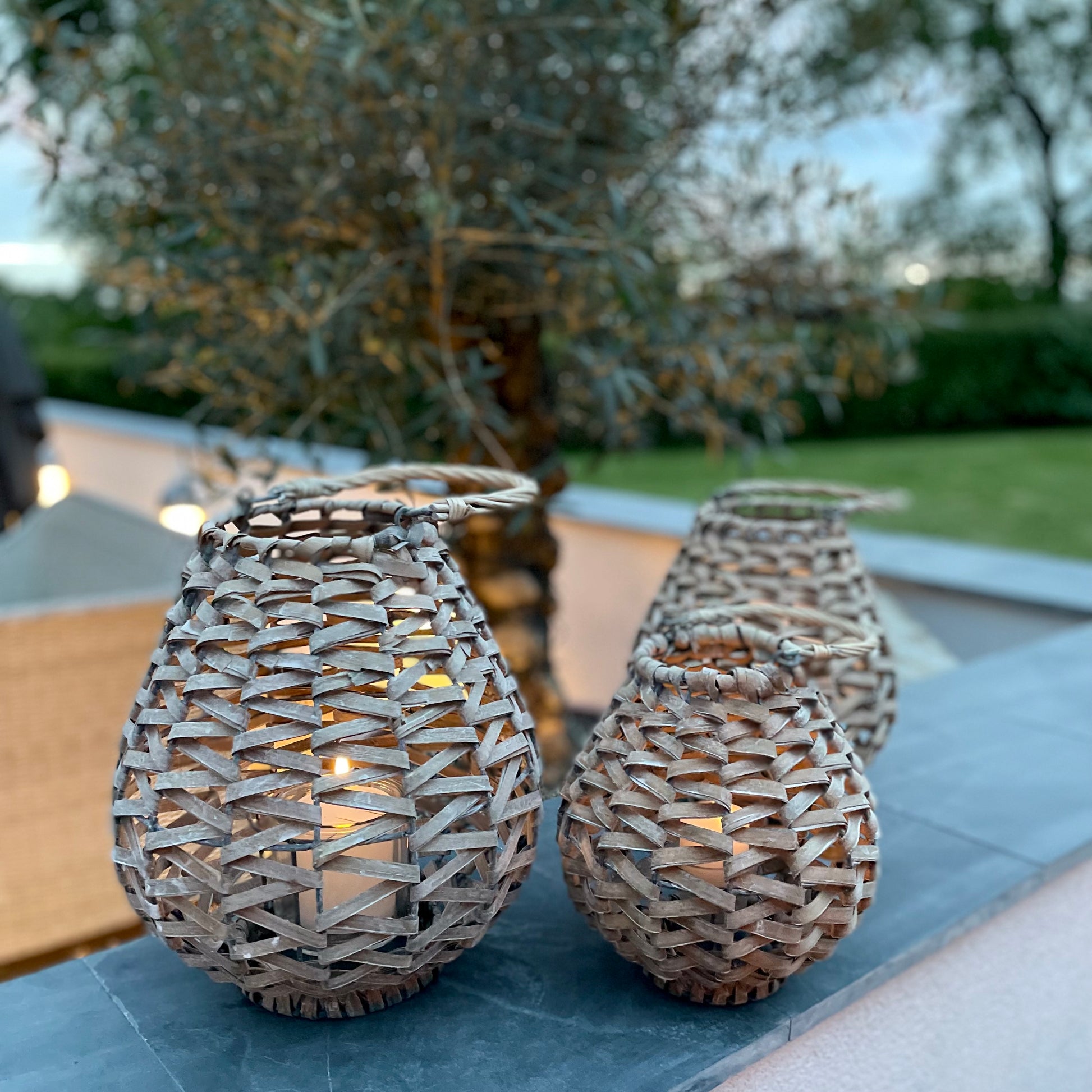 Teardrop shaped rattan lantern with glass insert, styled with a candle to add warm, relaxed lighting