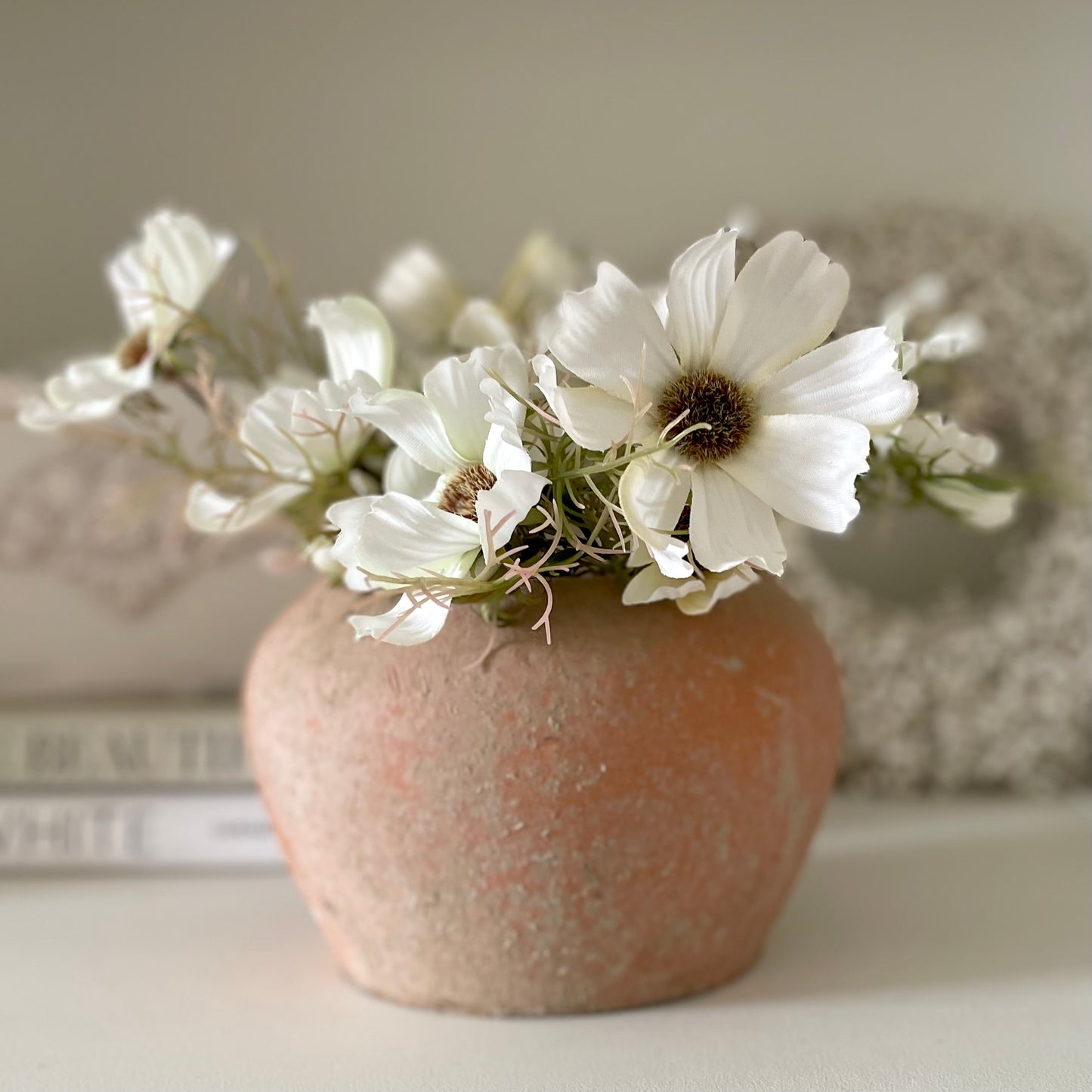 Rustic unglazed terracotta pot with natural finish, styled with a white cosmos spray.