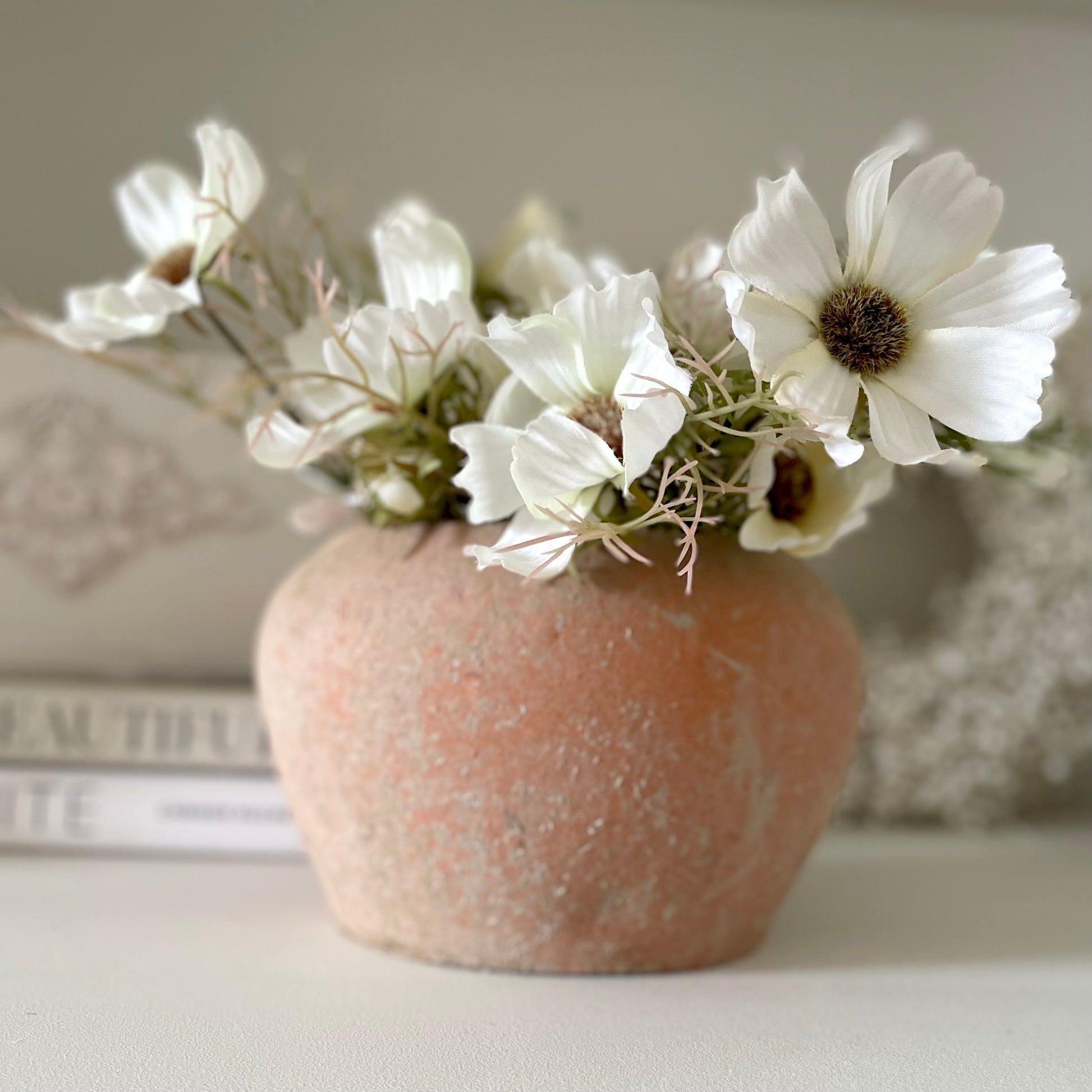 Unglazed terracotta pot with unique tones and details. Styled on a shelf with a book and cosmos spray.