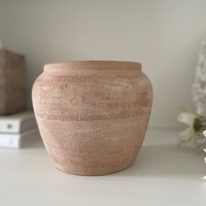 Light terracotta plant pot with rustic, unglazed texture. Styled on a shelf with books and white cosmos flowers.