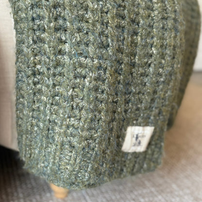 Decorative deep green throw with rich melange texture, perfect for cosy layering in neutral or seasonal interiors.