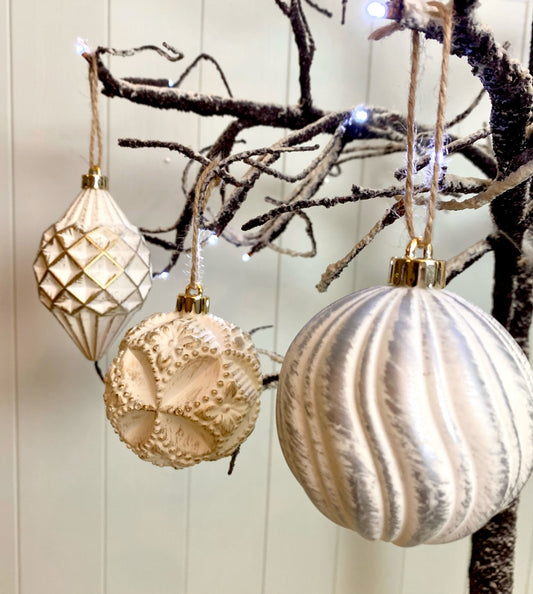 Off white vintage baubles hanging on a snow branch tree.