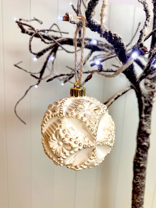 Picture of vintage style bauble hanging on a snowy branch.