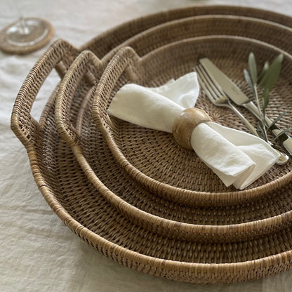 Set of white linen napkins for dining table styled in a rattan tray with handles.