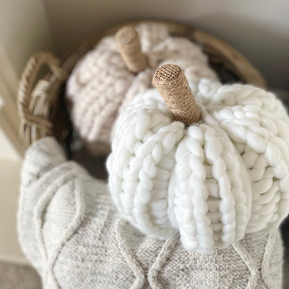 Oatmeal chunky knitted pumpkin with hessian twine wrapped stalk styled on a basket with throw.