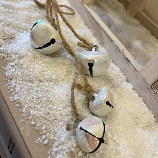 Close up of shimmering christmas bells ready for hanging. Styled on a snowy christmas scene.