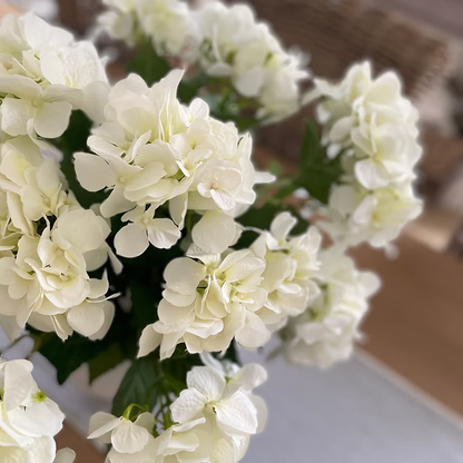 White faux hydrangea bouquet with seven flower heads, styled in a vase for a neutral home interior.