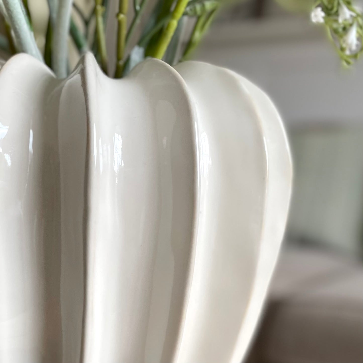 close up of white glazed olivia vase, styled in a cosy living room.