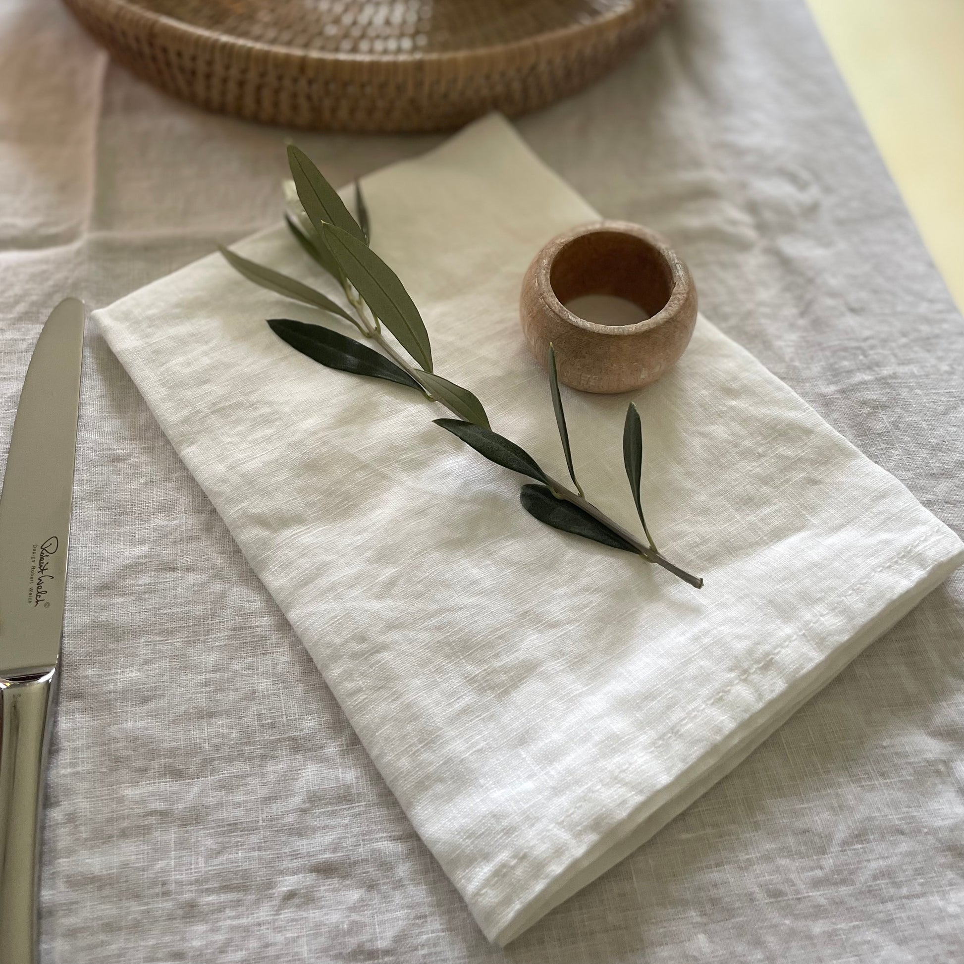 Classic white linen napkins paired with matching tablecloth and a wooden napkin ring.