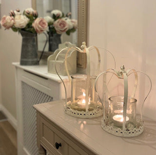 Antique style distressed white metal crown candle holders with removable glass insert, styled on a console table.