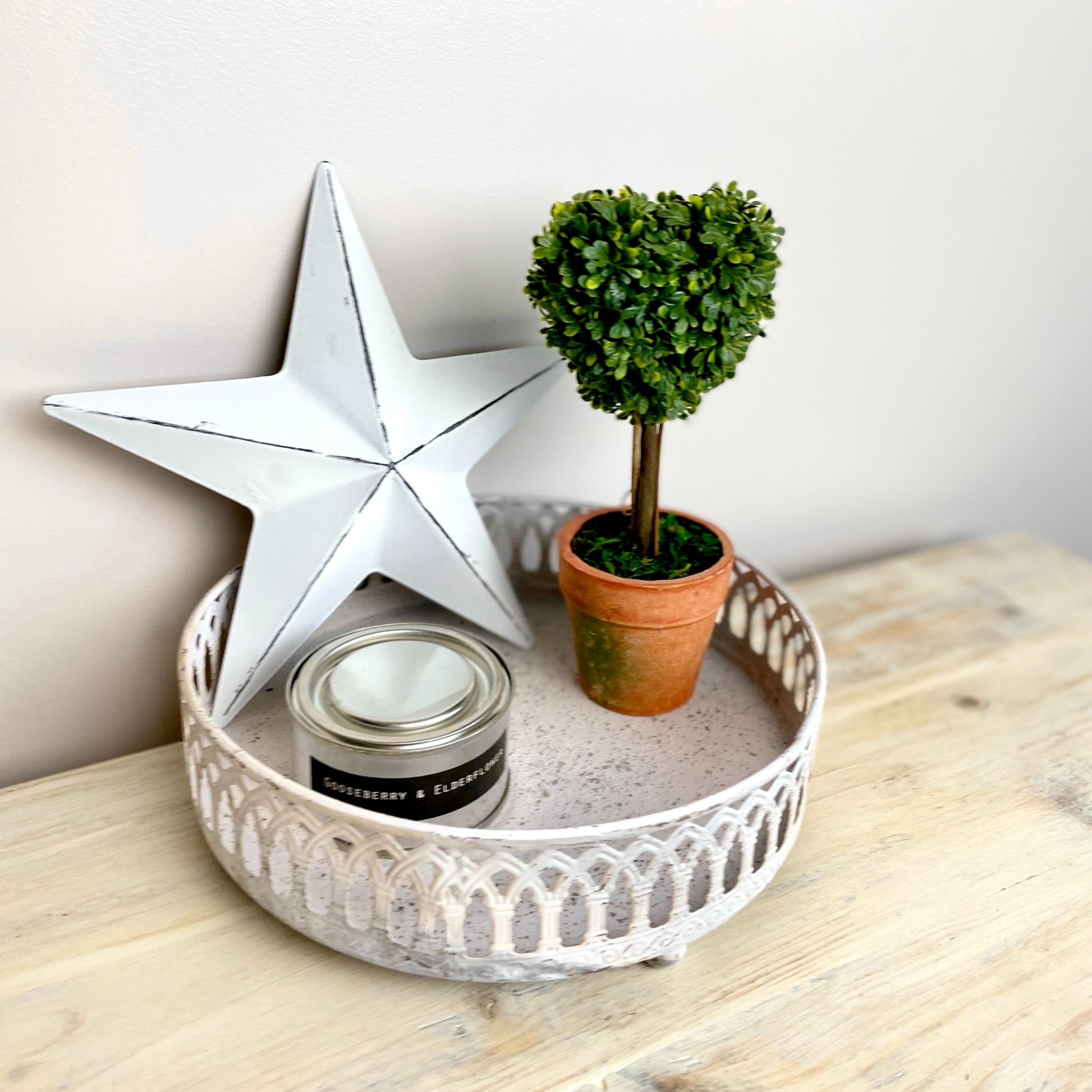 White washed rustic metal trays styled with candles and ornaments on a wooden console, adding vintage charm to a calm, country inspired interior.