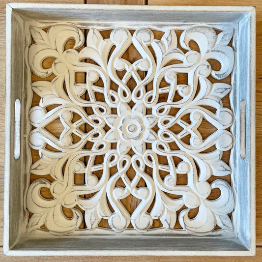 Decorative wooden tray with intricate carvings on a wooden surface