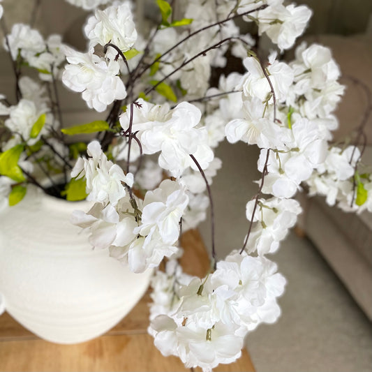 Artificial cherry blossom stem with delicate white flowers and cascading branches for a soft, timeless look.