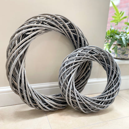 Grey white washed rattan wreaths with entwined design. Small and large, styled on a neutral wall.