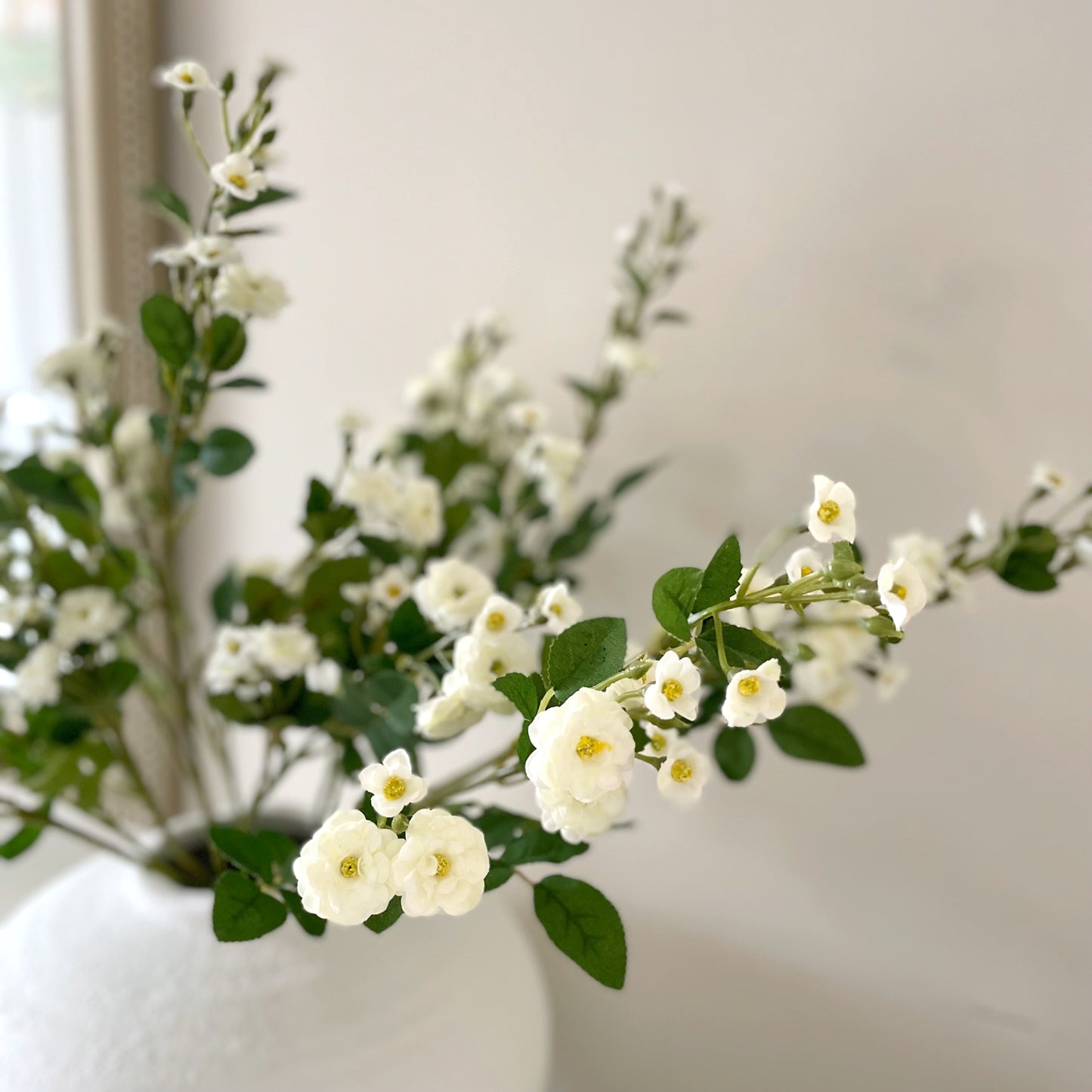 Wild Meadow White Rose Stem with delicate white flowers, soft yellow centres, and realistic green leaves, styled in a vase for timeless home decor.