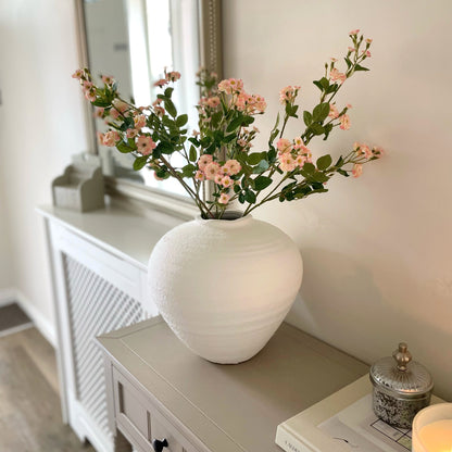 wild meadow rose faux stem styled in a matte white vase on a console table in a hallway.