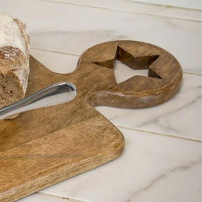 Handcrafted chunky mango wood chopping board with round handle and star cut out detail, styled on a rustic kitchen counter.