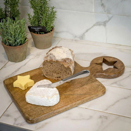 Handcrafted chunky mango wood chopping board with round handle and star cut out detail, styled on a rustic kitchen counter.