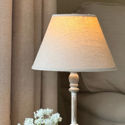 Table lamp with a textured shade on a wooden base in a cosy room setting.