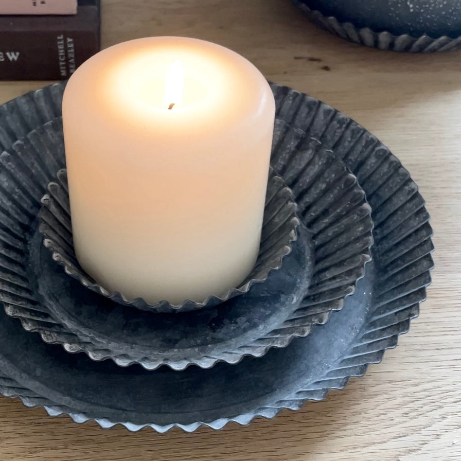 Rustic fluted zinc plate styled with a candle on a neutral table.